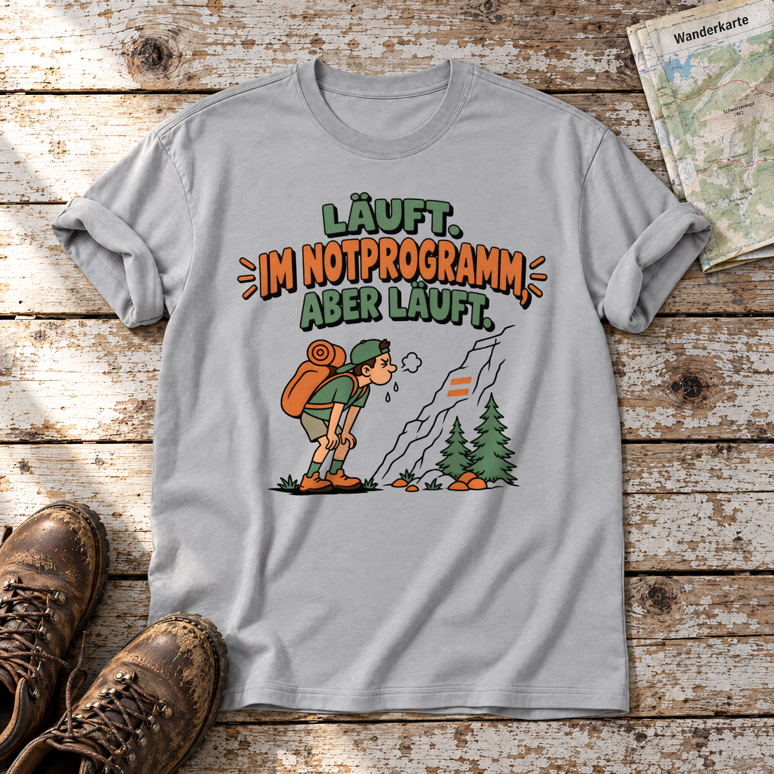 Im Notprogramm, aber läuft – T-Shirt Unisex in Hellgrau, flach liegend auf alten Holzbrettern mit Wanderschuhen und Wanderkarte.