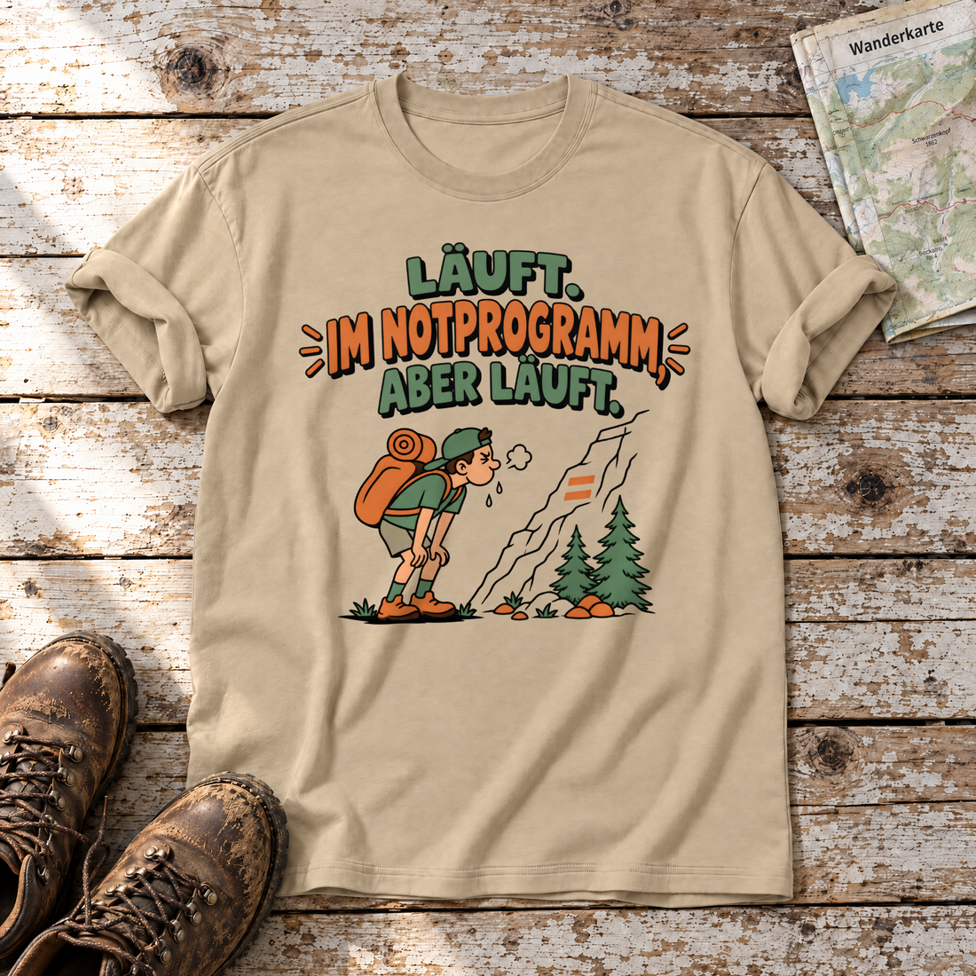 Im Notprogramm, aber läuft – T-Shirt Unisex in Sand, flach liegend auf alten Holzbrettern mit Wanderschuhen und Wanderkarte.