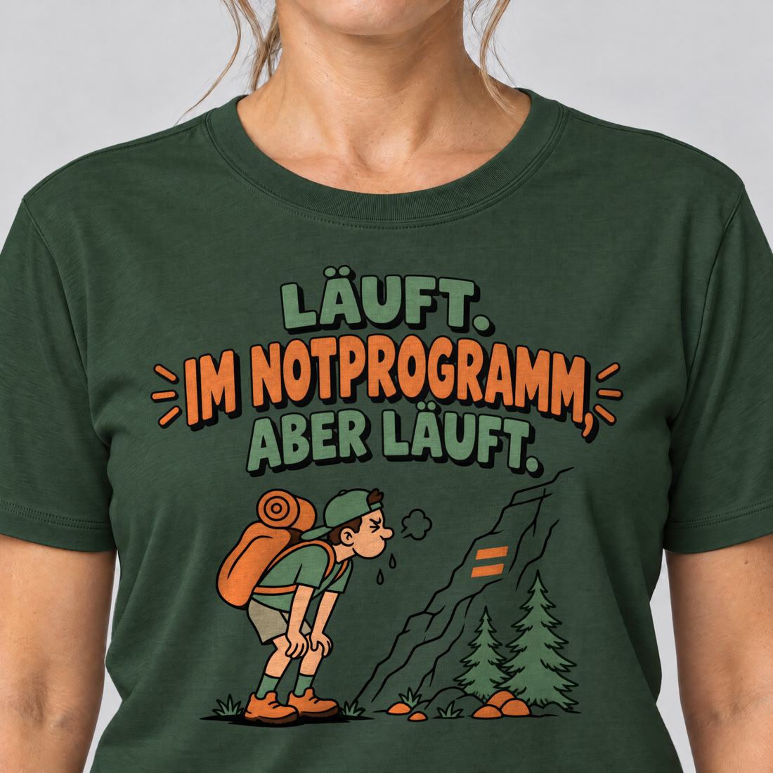 Nahaufnahme des Drucks: Im Notprogramm, aber läuft – T-Shirt Unisex in Flaschengrün, von einer Frau getragen