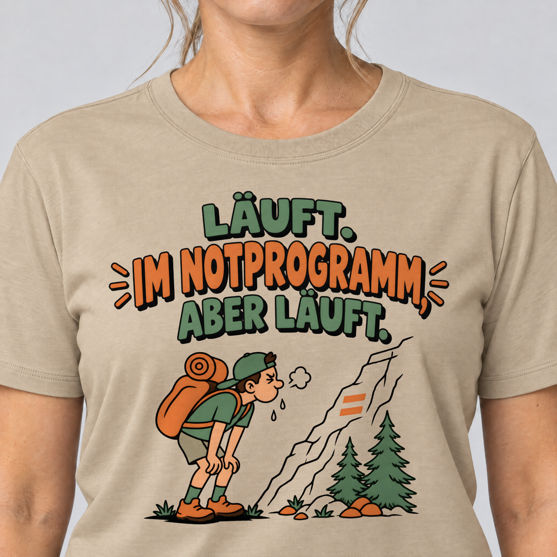 Nahaufnahme des Drucks: Im Notprogramm, aber läuft – T-Shirt Unisex in Sand, von einer Frau getragen