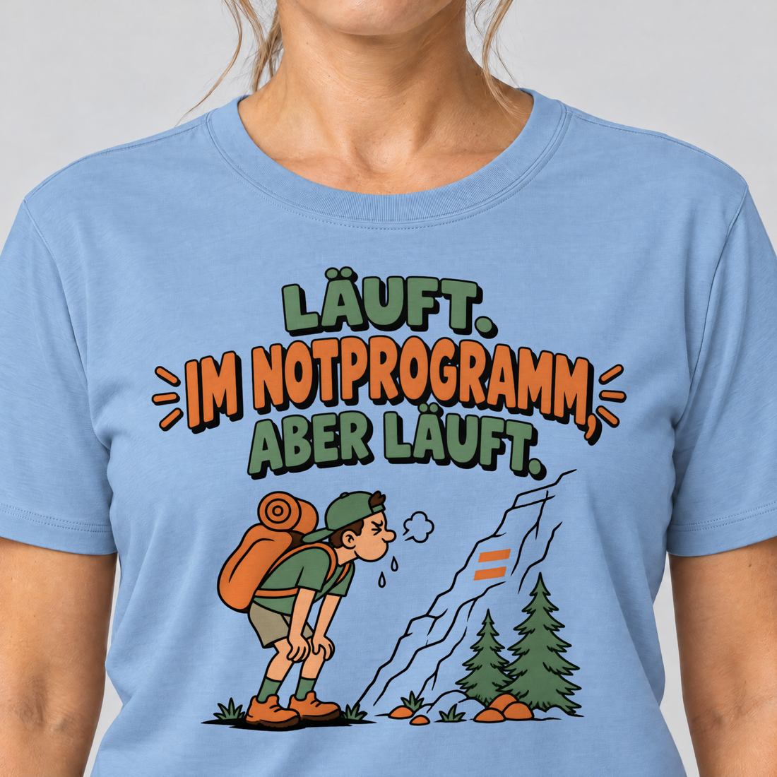Nahaufnahme des Drucks: Im Notprogramm, aber läuft – T-Shirt Unisex in Himmelblau, von einer Frau getragen