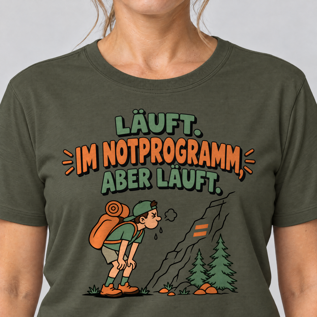 Nahaufnahme des Drucks: Im Notprogramm, aber läuft – T-Shirt Unisex in Oliv, von einer Frau getragen
