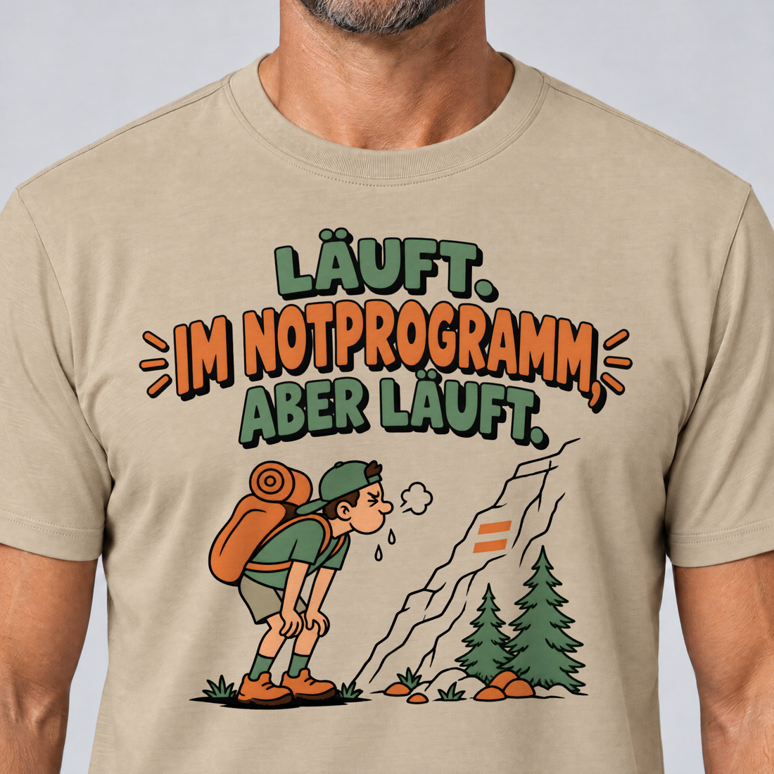 Nahaufnahme des Drucks: Im Notprogramm, aber läuft – T-Shirt Unisex in Sand, von einem Mann getragen
