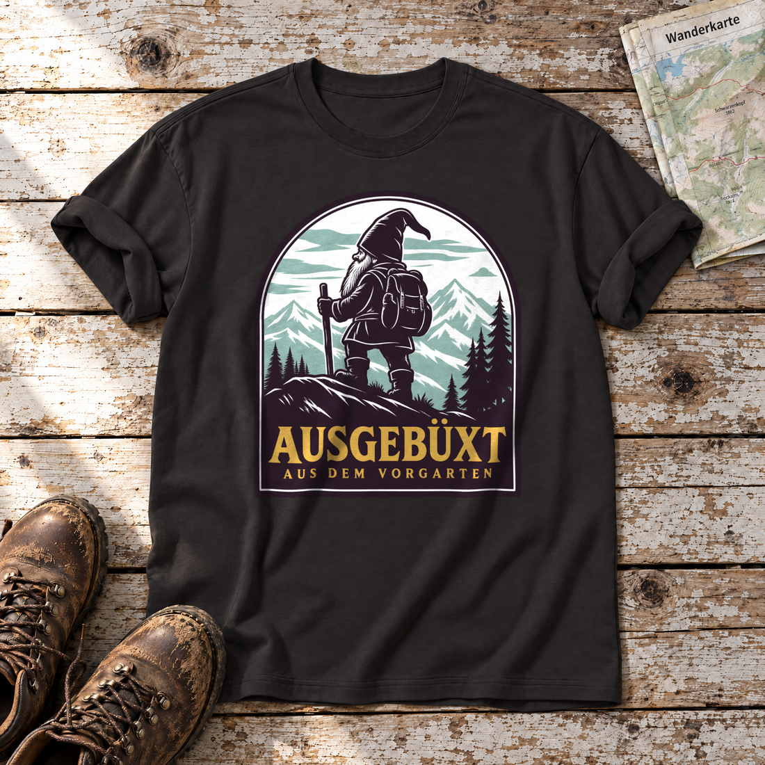 Ausgebüxt aus dem Vorgarten – T-Shirt Unisex in Schwarz, flach liegend auf alten Holzbrettern mit Wanderschuhen und Wanderkarte.