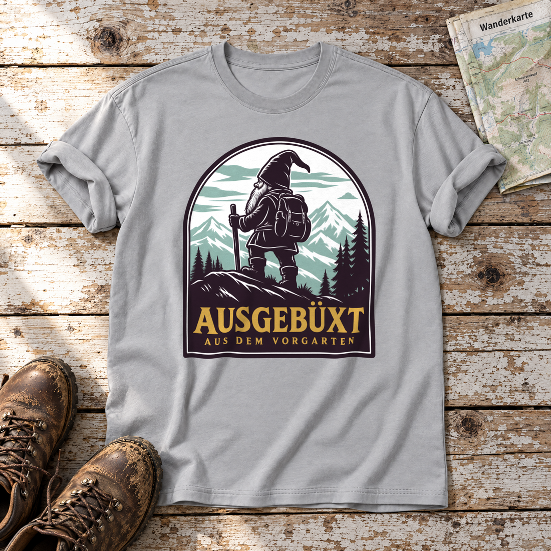 Ausgebüxt aus dem Vorgarten – T-Shirt Unisex in Hellgrau, flach liegend auf alten Holzbrettern mit Wanderschuhen und Wanderkarte.