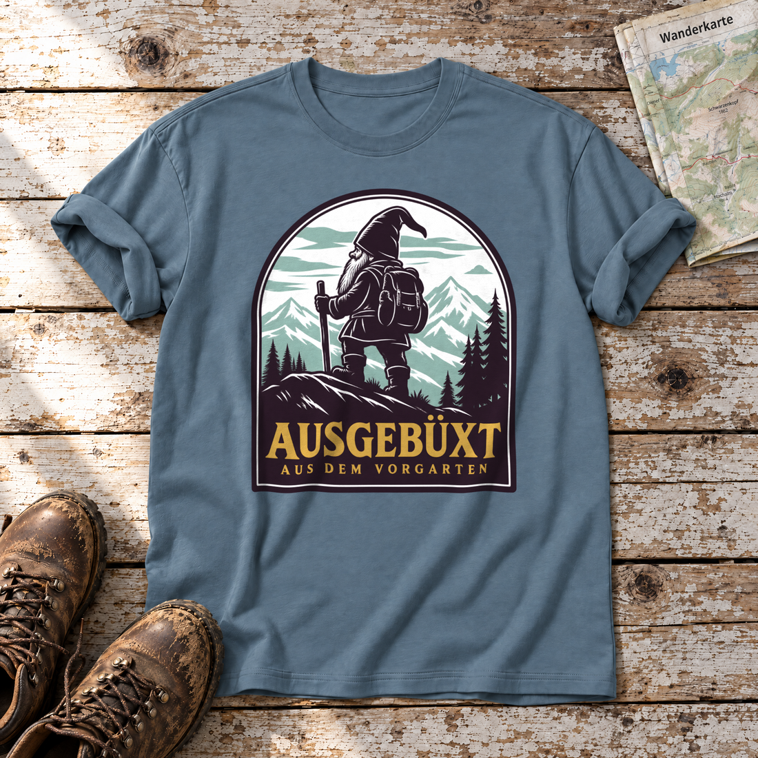 Ausgebüxt aus dem Vorgarten – T-Shirt Unisex in Steinblau, flach liegend auf alten Holzbrettern mit Wanderschuhen und Wanderkarte.