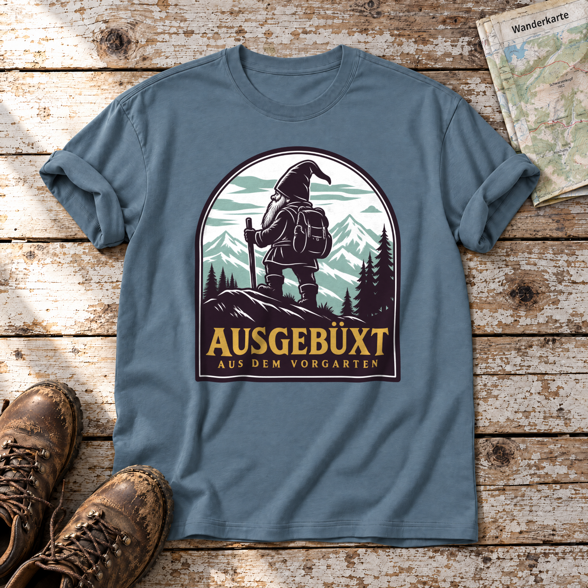 Ausgebüxt aus dem Vorgarten – T-Shirt Unisex in Steinblau, flach liegend auf alten Holzbrettern mit Wanderschuhen und Wanderkarte.