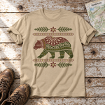 Bär im Alpenornament – T-Shirt Unisex in Sand, flach liegend auf alten Holzbrettern mit Wanderschuhen und Wanderkarte.