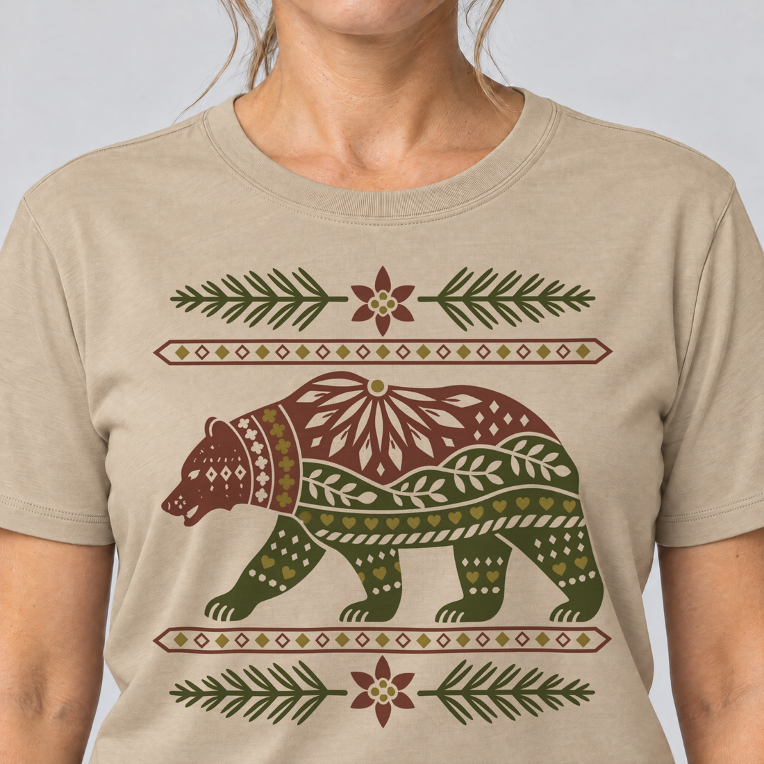 Nahaufnahme des Drucks: Bär im Alpenornament – T-Shirt Unisex in Sand, von einer Frau getragen