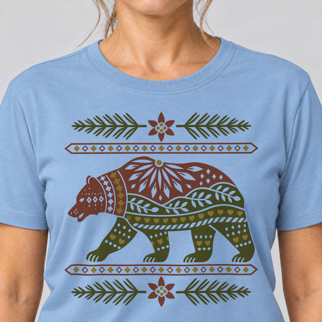 Nahaufnahme des Drucks: Bär im Alpenornament – T-Shirt Unisex in Himmelblau, von einer Frau getragen