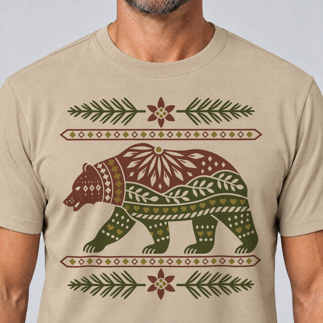 Nahaufnahme des Drucks: Bär im Alpenornament – T-Shirt Unisex in Sand, von einem Mann getragen