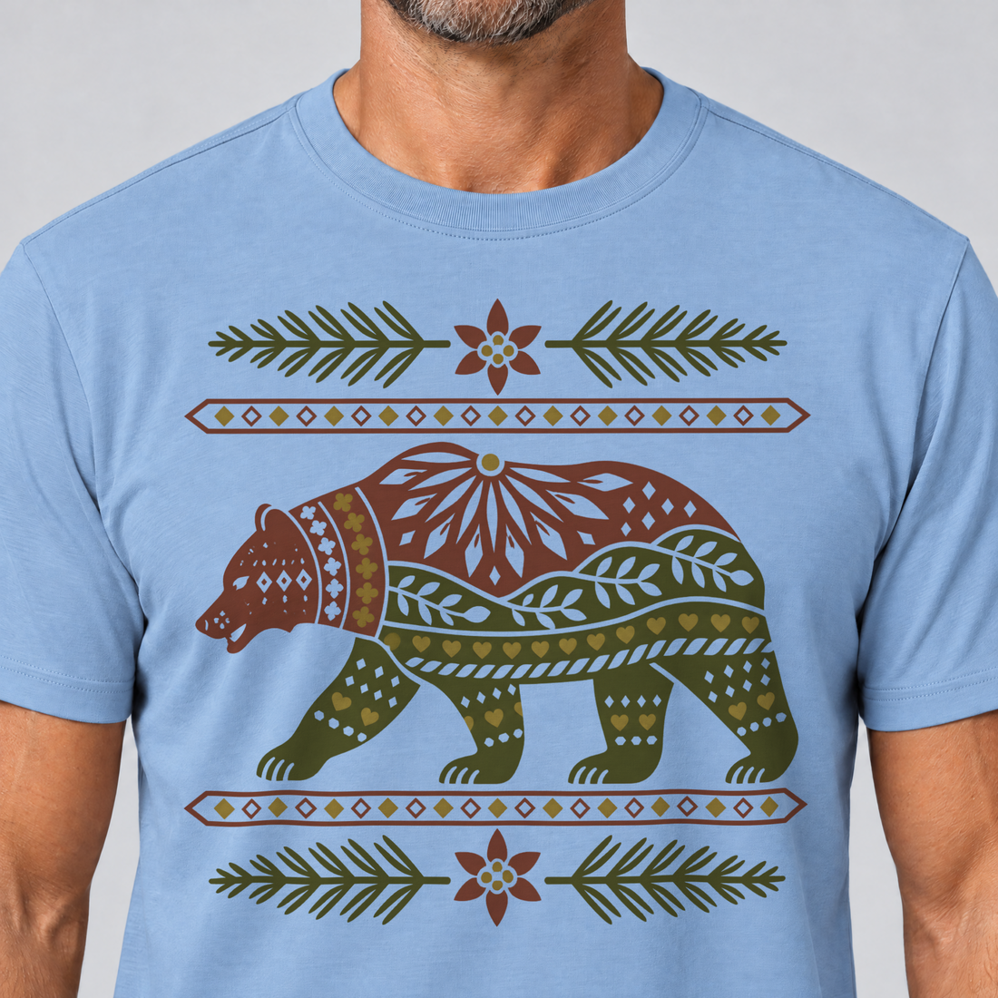 Nahaufnahme des Drucks: Bär im Alpenornament – T-Shirt Unisex in Himmelblau, von einem Mann getragen