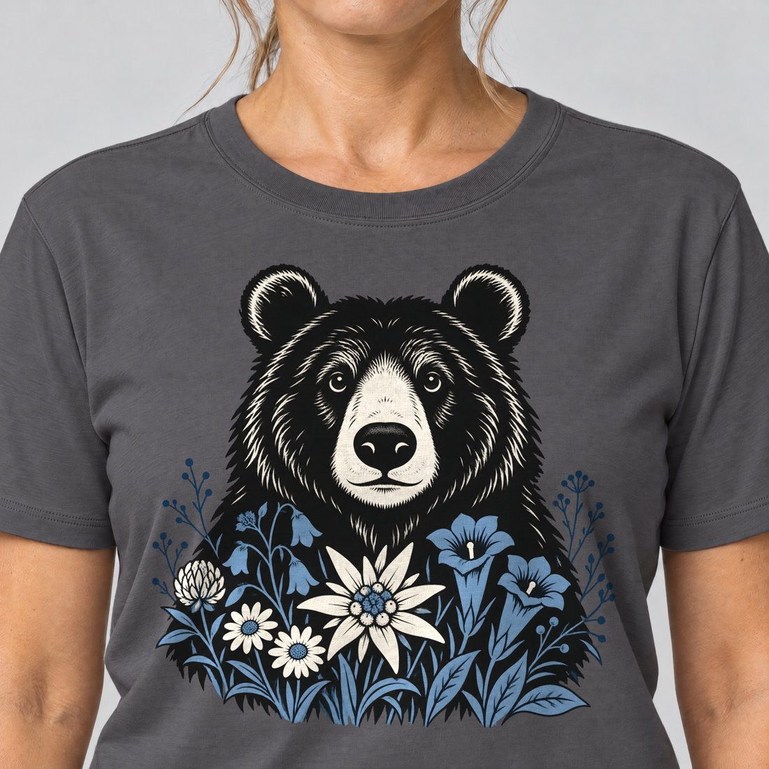Nahaufnahme des Drucks: Bär in der Alpenwiese – T-Shirt Unisex in Dunkelgrau, von einer Frau getragen