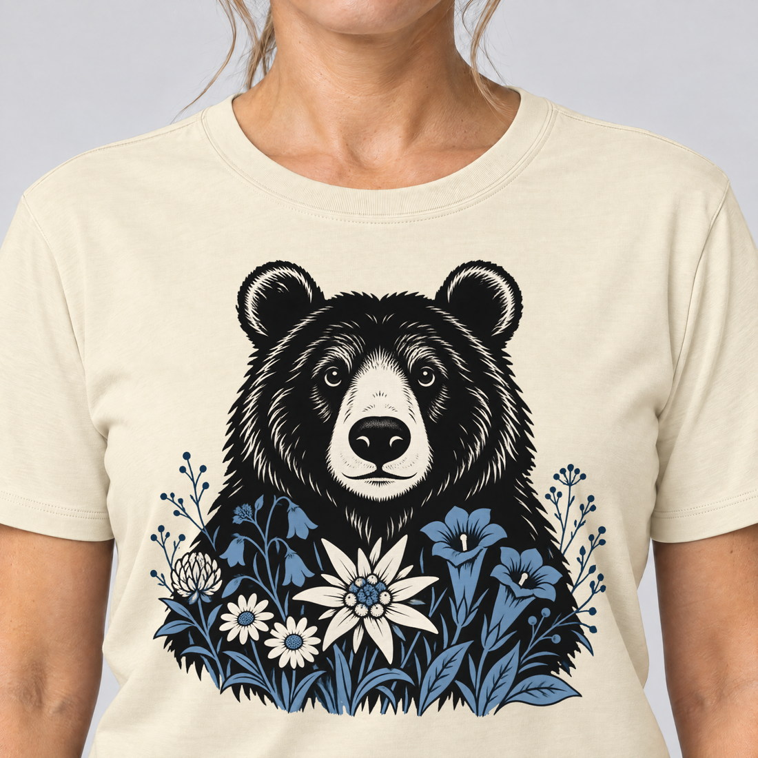Nahaufnahme des Drucks: Bär in der Alpenwiese – T-Shirt Unisex in Natur, von einer Frau getragen