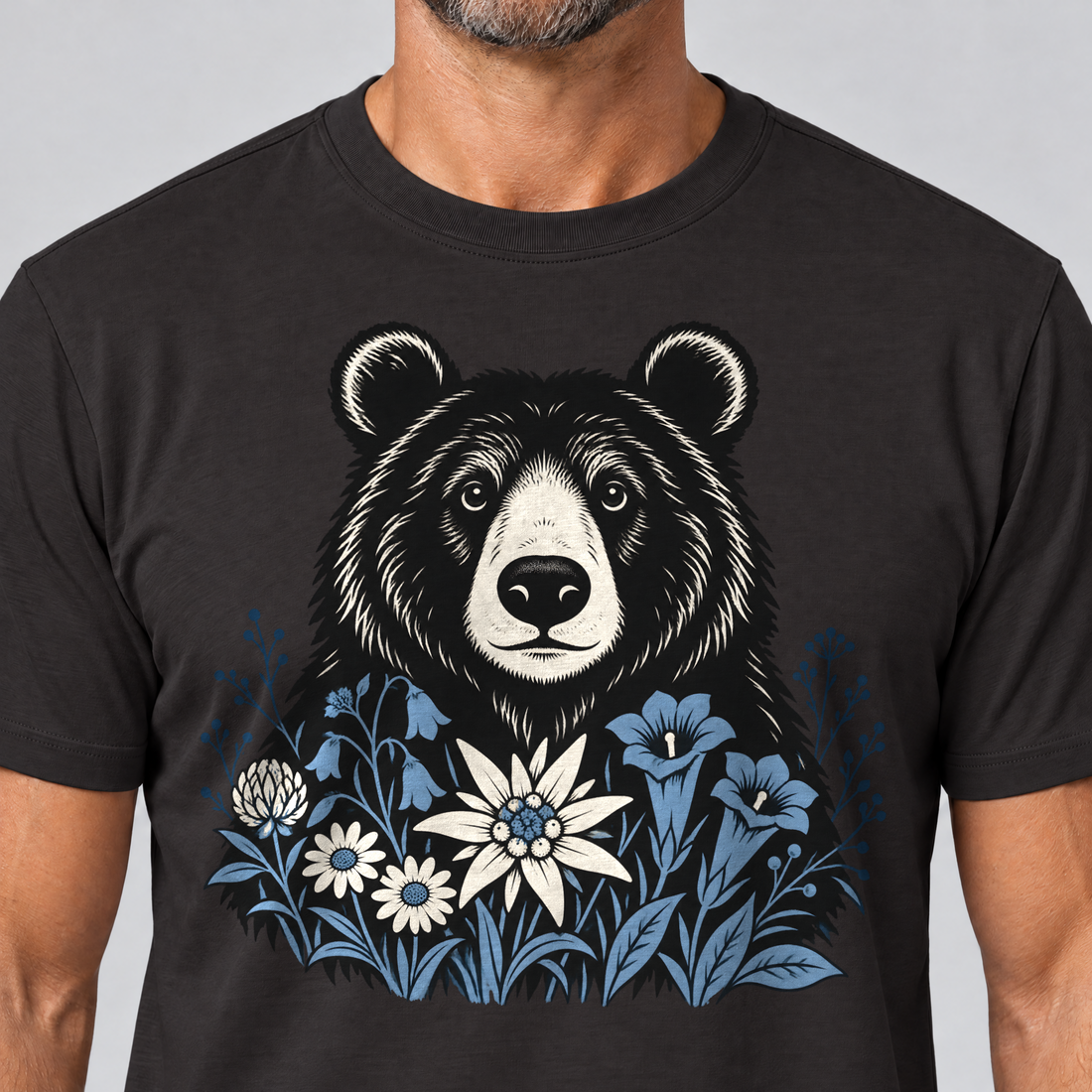 Nahaufnahme des Drucks: Bär in der Alpenwiese – T-Shirt Unisex in Schwarz, von einem Mann getragen