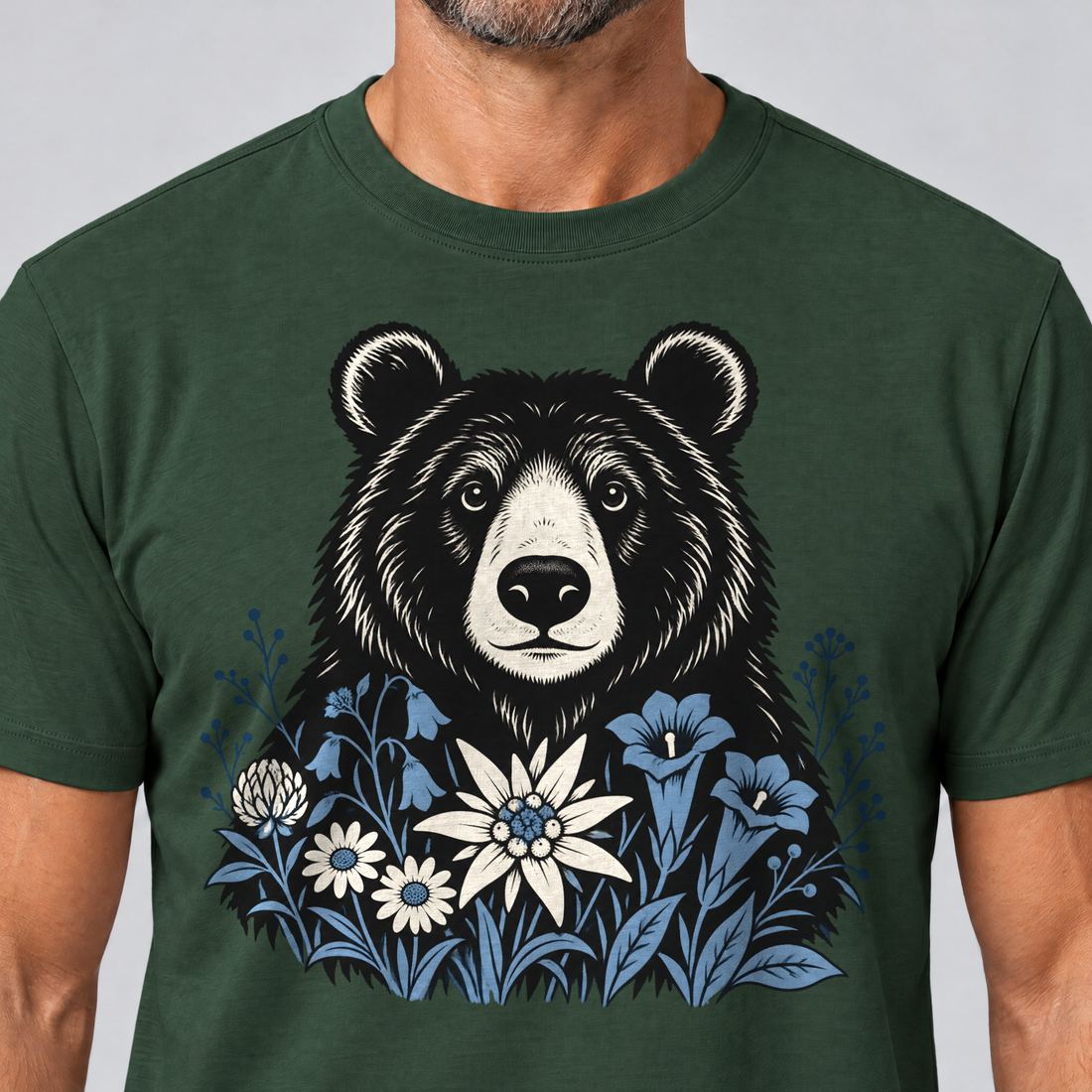 Nahaufnahme des Drucks: Bär in der Alpenwiese – T-Shirt Unisex in Flaschengrün, von einem Mann getragen