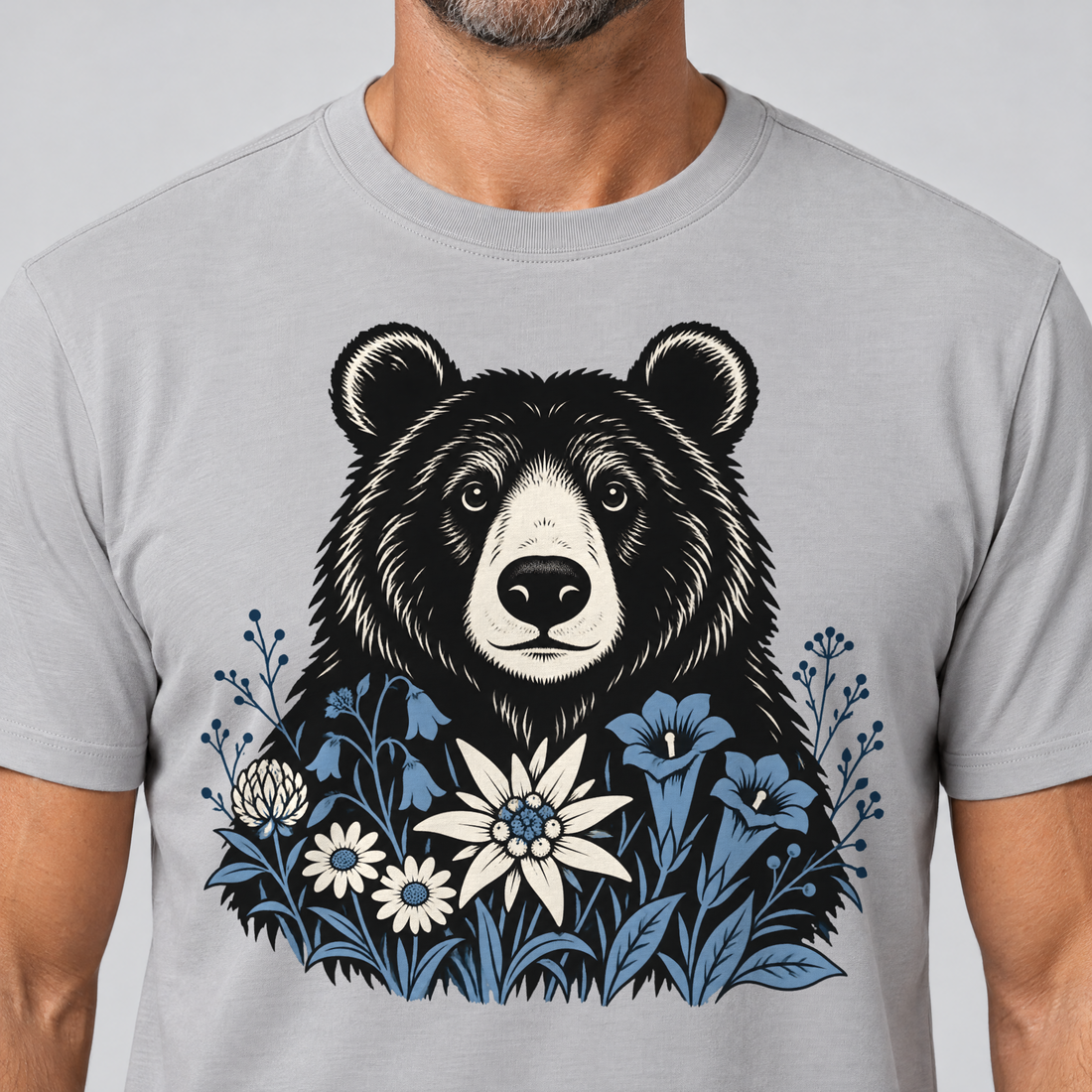 Nahaufnahme des Drucks: Bär in der Alpenwiese – T-Shirt Unisex in Hellgrau, von einem Mann getragen
