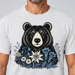 Nahaufnahme des Drucks: Bär in der Alpenwiese – T-Shirt Unisex in Weiß, von einem Mann getragen