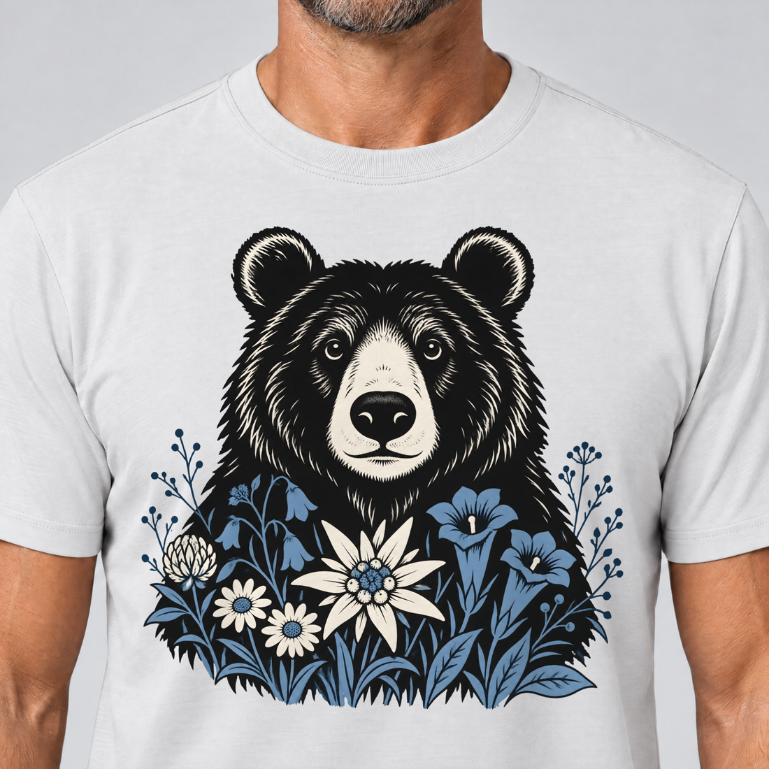 Nahaufnahme des Drucks: Bär in der Alpenwiese – T-Shirt Unisex in Weiß, von einem Mann getragen