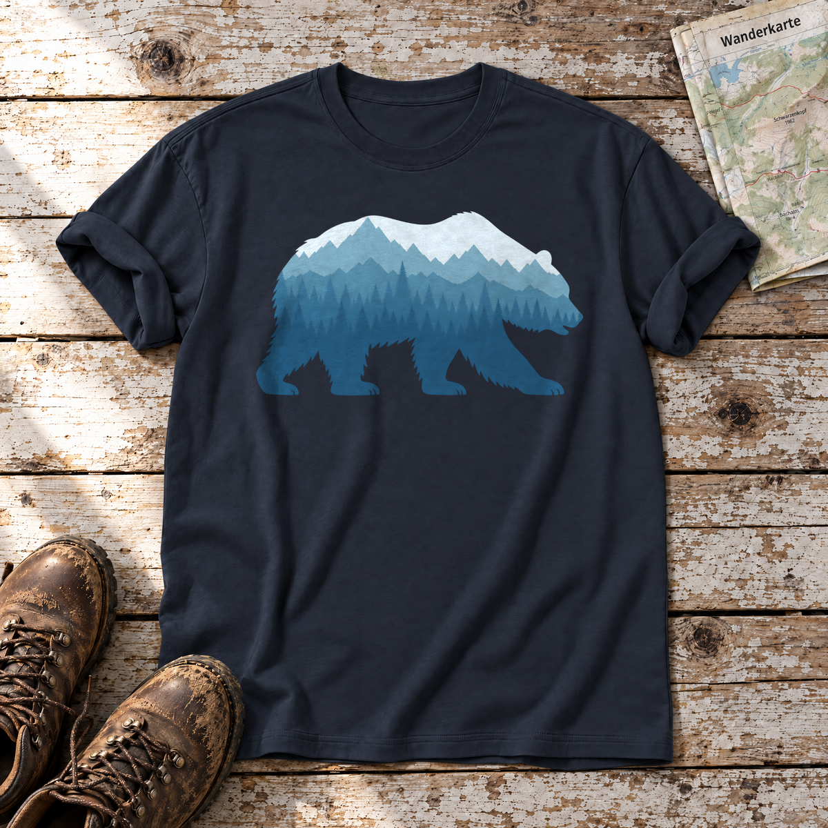 Bär im Bergwald – T-Shirt Unisex in Navy, flach liegend auf alten Holzbrettern mit Wanderschuhen und Wanderkarte.