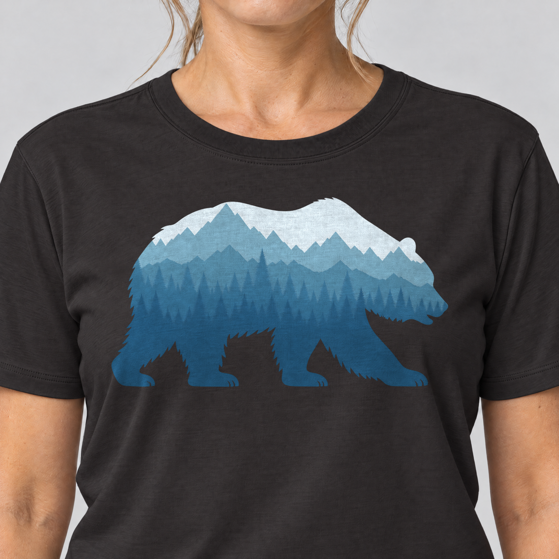 Nahaufnahme des Drucks: Bär im Bergwald – T-Shirt Unisex in Schwarz, von einer Frau getragen
