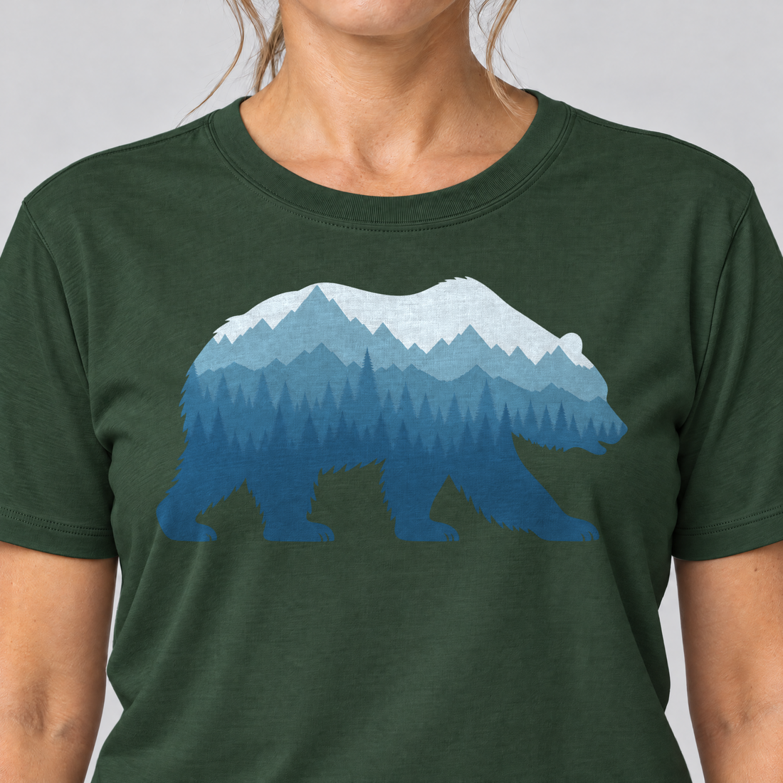 Nahaufnahme des Drucks: Bär im Bergwald – T-Shirt Unisex in Flaschengrün, von einer Frau getragen
