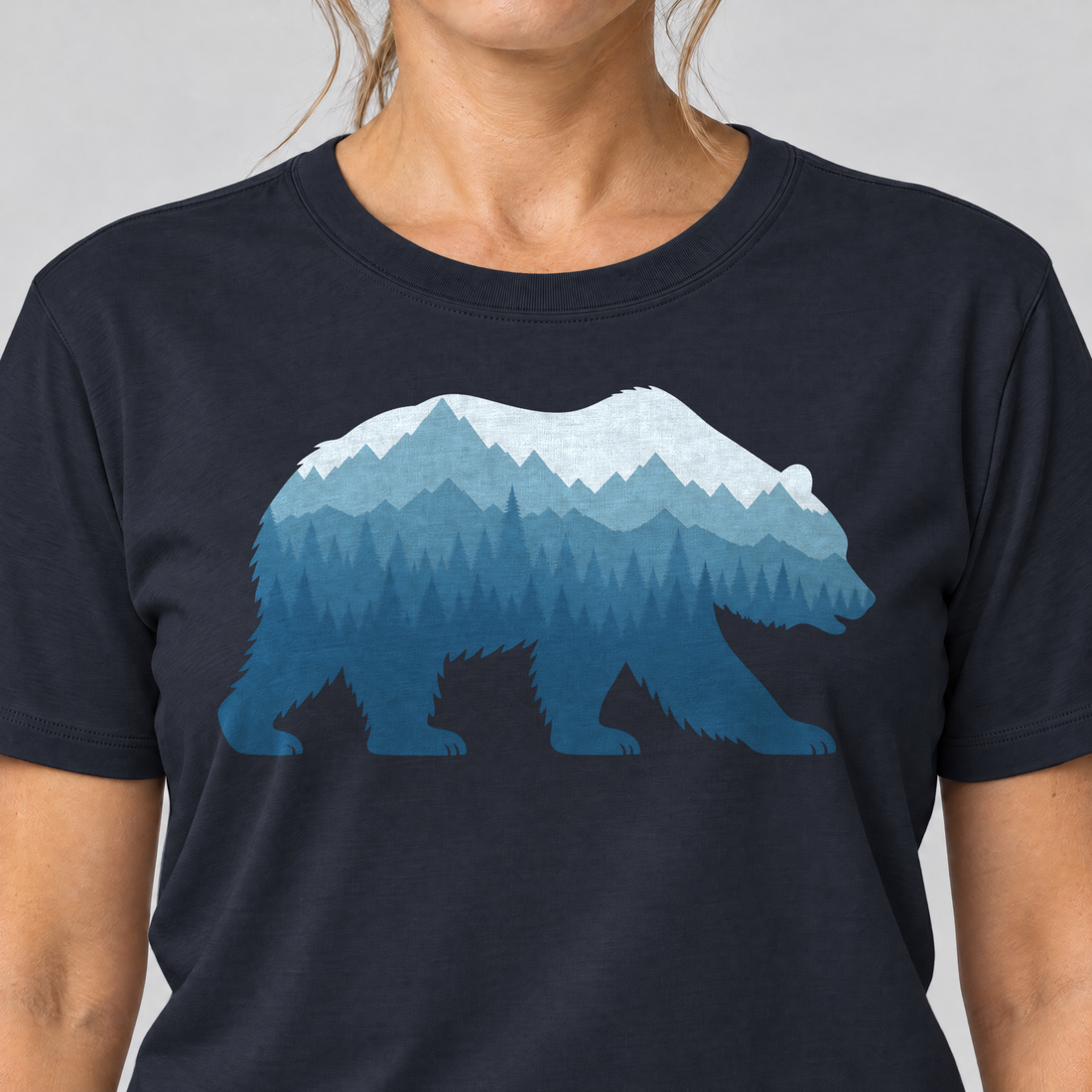 Nahaufnahme des Drucks: Bär im Bergwald – T-Shirt Unisex in Navy, von einer Frau getragen