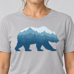 Nahaufnahme des Drucks: Bär im Bergwald – T-Shirt Unisex in Hellgrau, von einer Frau getragen
