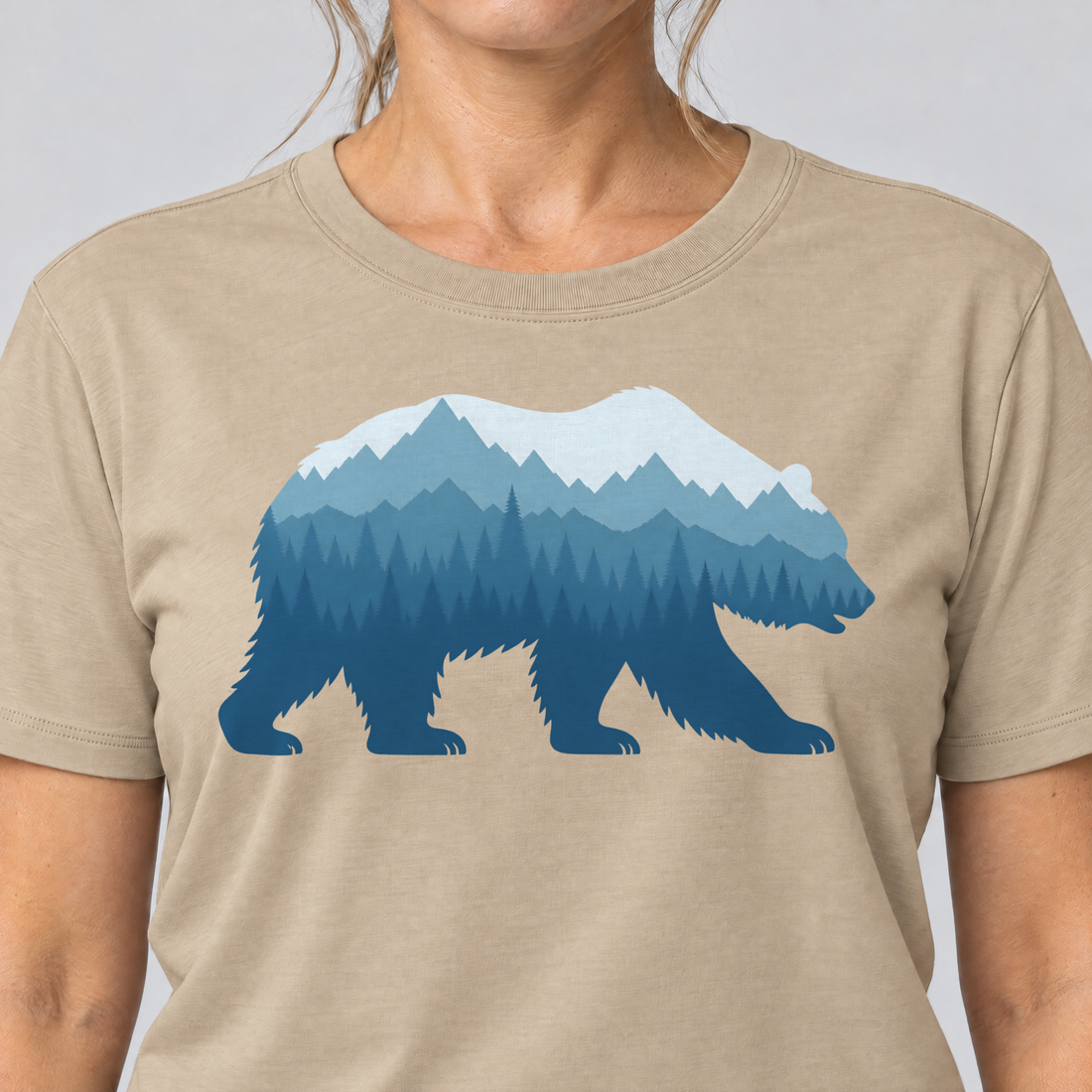 Nahaufnahme des Drucks: Bär im Bergwald – T-Shirt Unisex in Sand, von einer Frau getragen