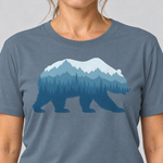 Nahaufnahme des Drucks: Bär im Bergwald – T-Shirt Unisex in Steinblau, von einer Frau getragen
