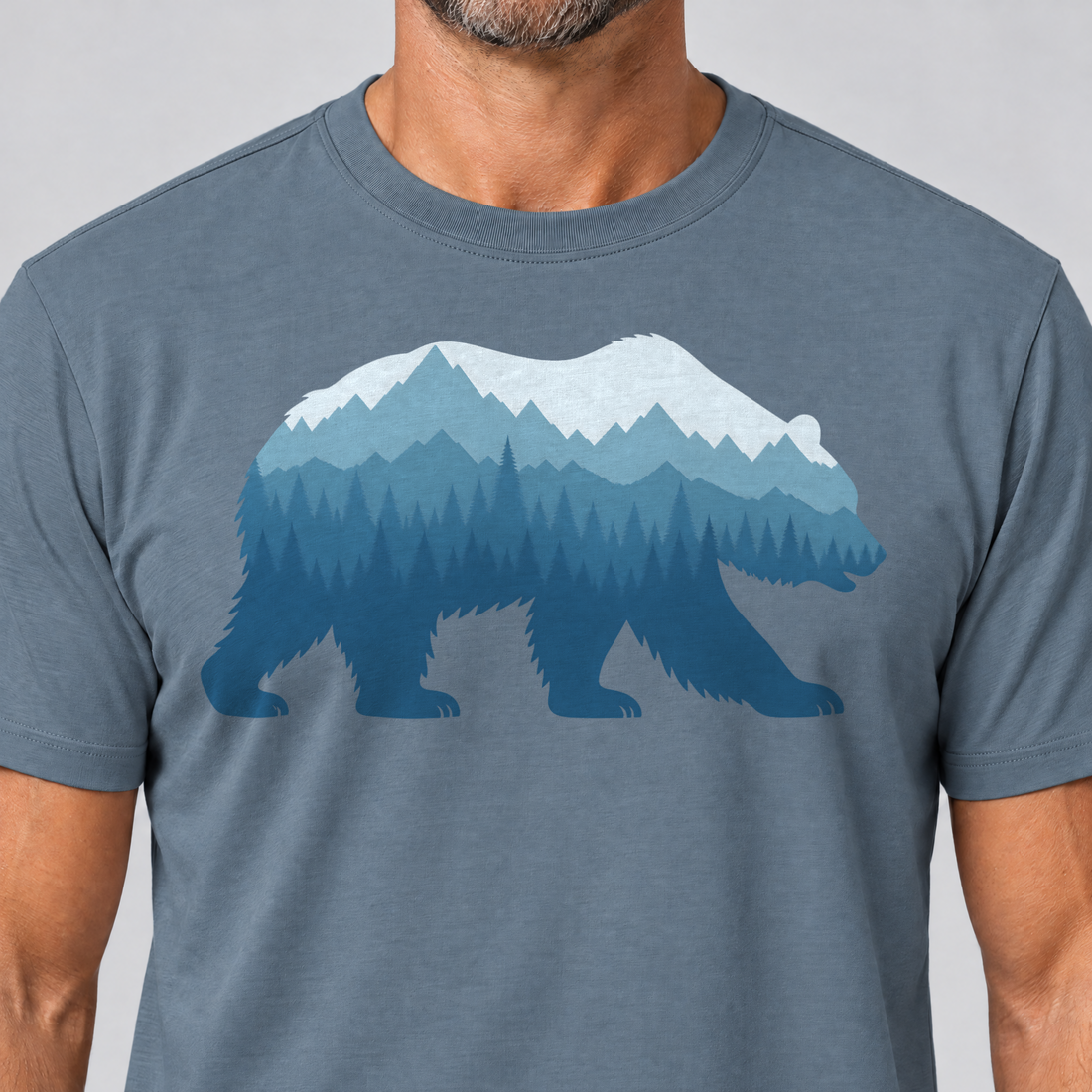 Nahaufnahme des Drucks: Bär im Bergwald – T-Shirt Unisex in Steinblau, von einem Mann getragen