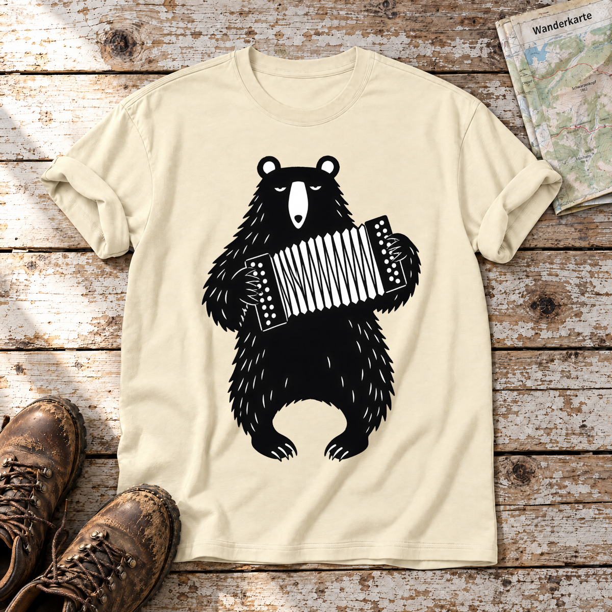 Bär mit Steirischer – T-Shirt Unisex in Natur, flach liegend auf alten Holzbrettern mit Wanderschuhen und Wanderkarte.