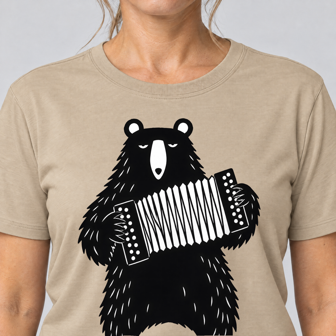 Nahaufnahme des Drucks: Bär mit Steirischer – T-Shirt Unisex in Sand, von einer Frau getragen