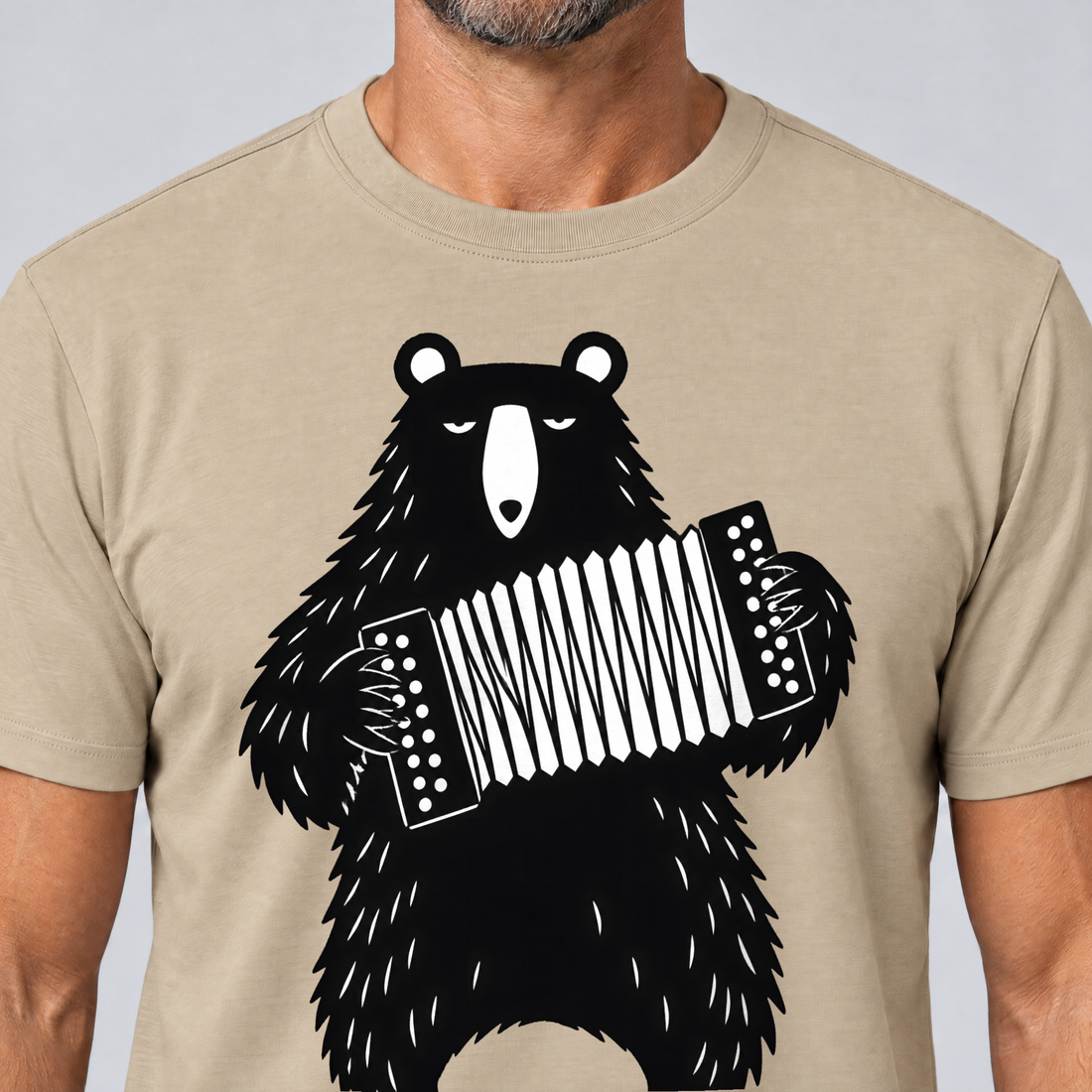 Nahaufnahme des Drucks: Bär mit Steirischer – T-Shirt Unisex in Sand, von einem Mann getragen