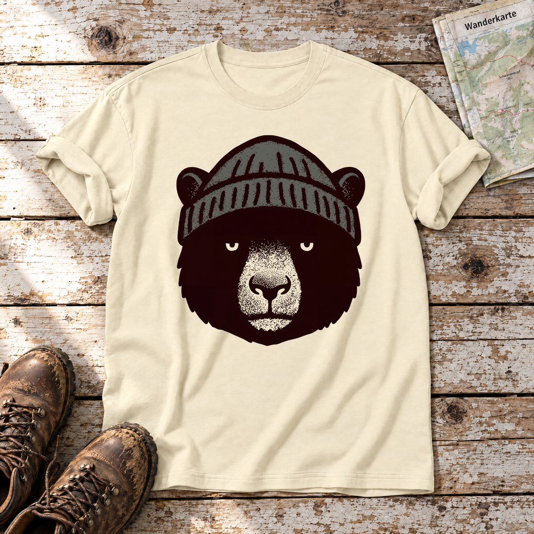 Bär mit Strickmütze – T-Shirt Unisex in Natur, flach liegend auf alten Holzbrettern mit Wanderschuhen und Wanderkarte.