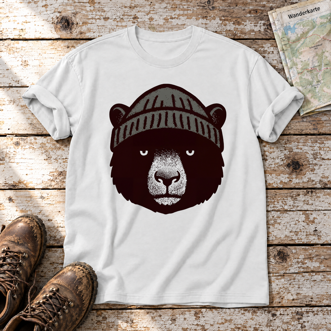 Bär mit Strickmütze – T-Shirt Unisex in Weiß, flach liegend auf alten Holzbrettern mit Wanderschuhen und Wanderkarte.
