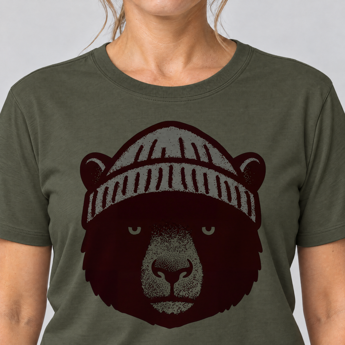 Nahaufnahme des Drucks: Bär mit Strickmütze – T-Shirt Unisex in Oliv, von einer Frau getragen