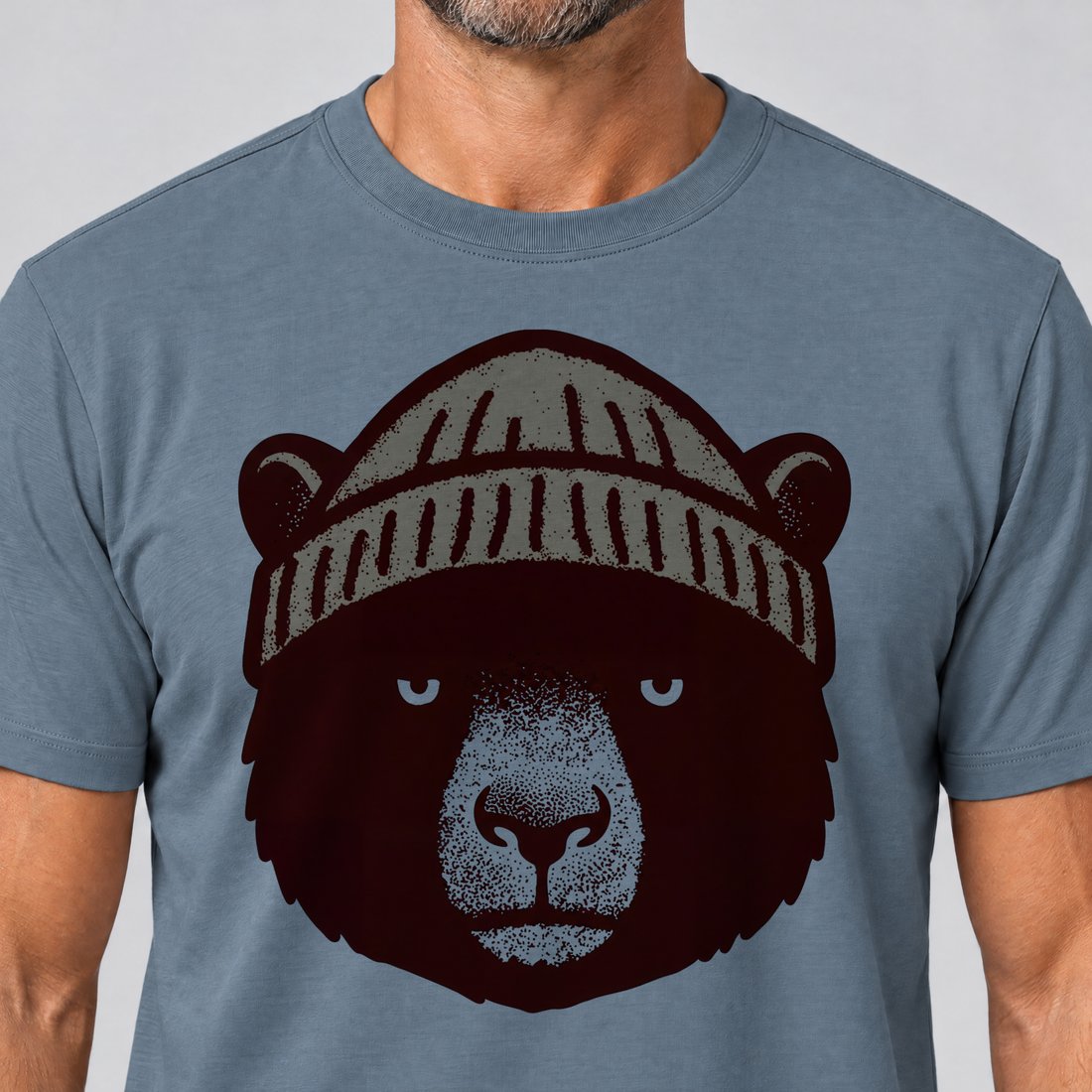 Nahaufnahme des Drucks: Bär mit Strickmütze – T-Shirt Unisex in Steinblau, von einem Mann getragen