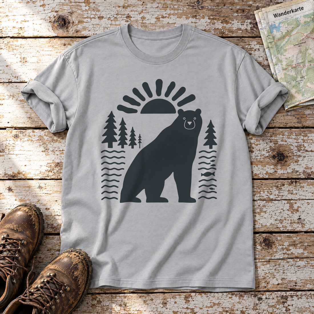 Bär im Sonnenbogen – T-Shirt Unisex in Hellgrau, flach liegend auf alten Holzbrettern mit Wanderschuhen und Wanderkarte.
