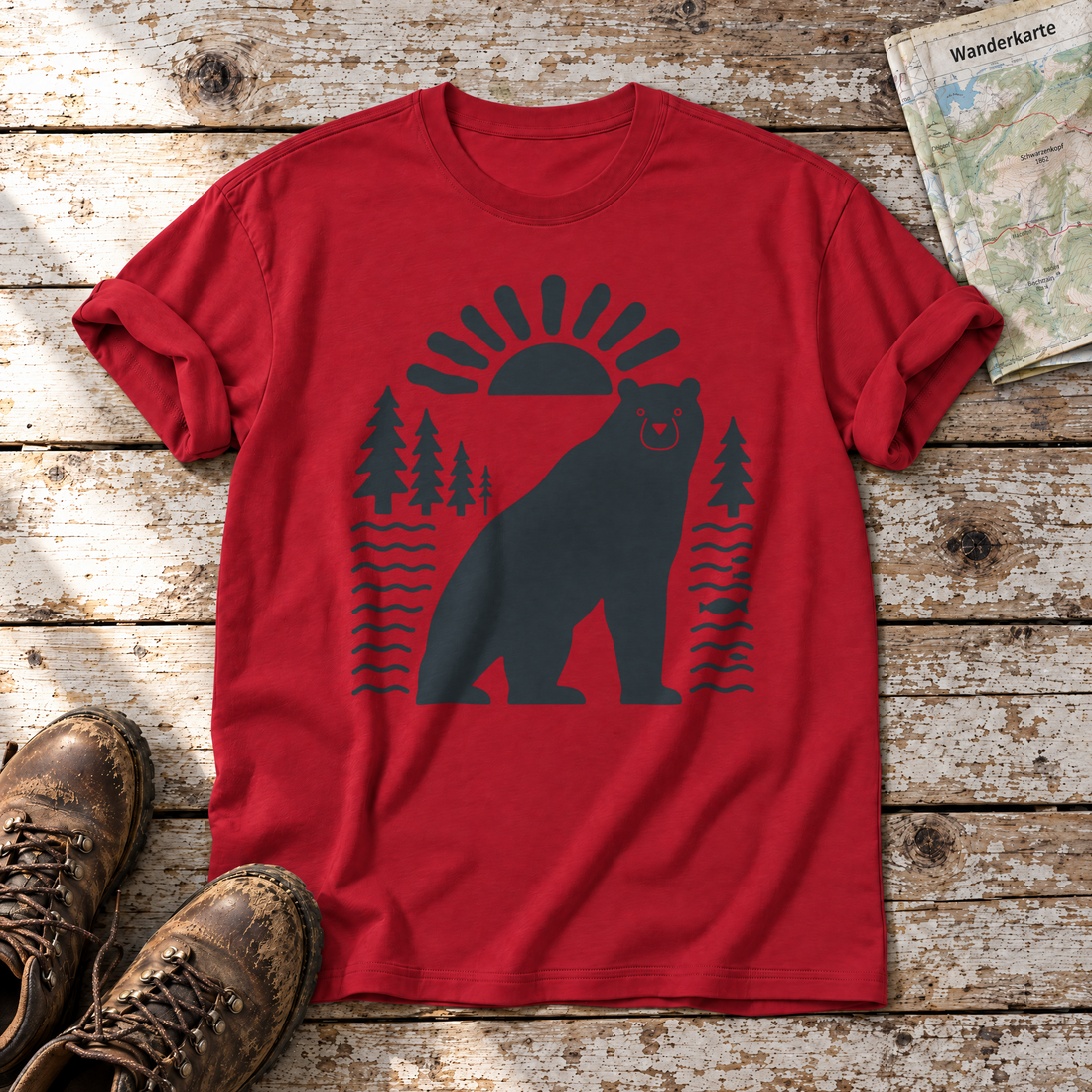Bär im Sonnenbogen – T-Shirt Unisex in Rot, flach liegend auf alten Holzbrettern mit Wanderschuhen und Wanderkarte.