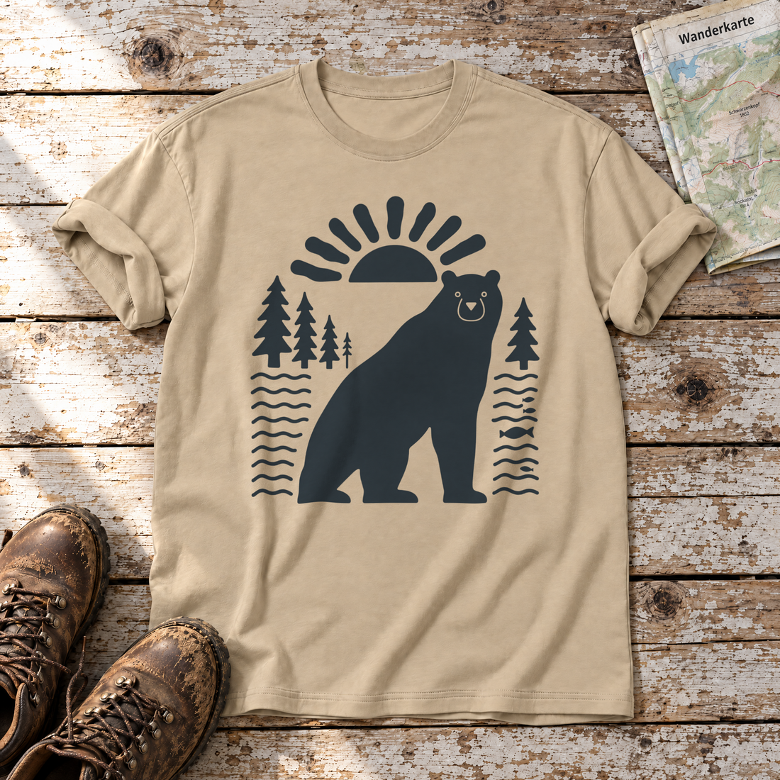 Bär im Sonnenbogen – T-Shirt Unisex in Sand, flach liegend auf alten Holzbrettern mit Wanderschuhen und Wanderkarte.