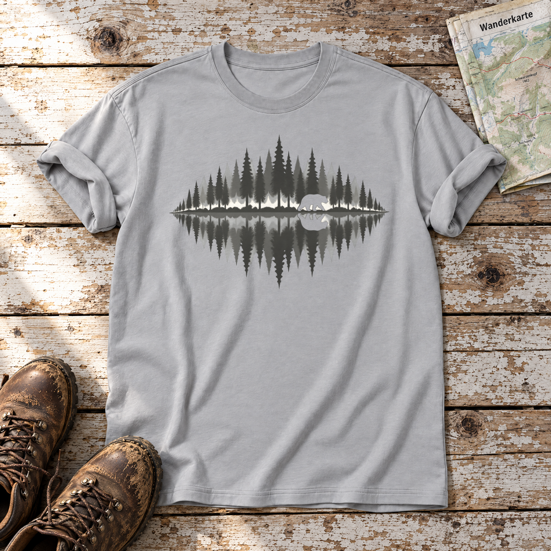 Bär am Waldsee – T-Shirt Unisex in Hellgrau, flach liegend auf alten Holzbrettern mit Wanderschuhen und Wanderkarte.