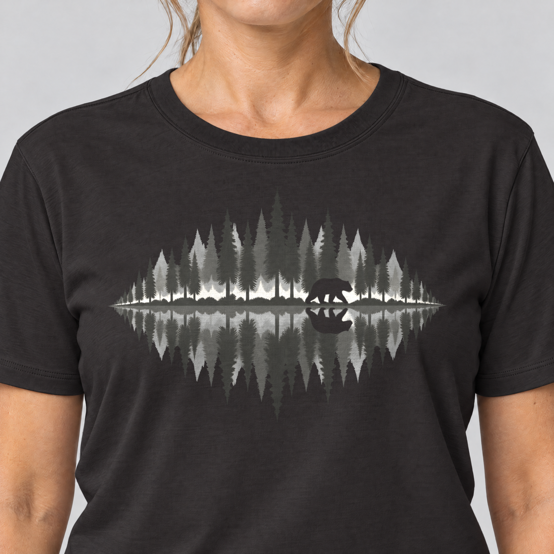 Nahaufnahme des Drucks: Bär am Waldsee – T-Shirt Unisex in Schwarz, von einer Frau getragen