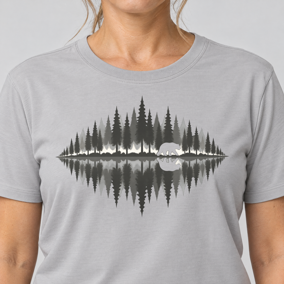 Nahaufnahme des Drucks: Bär am Waldsee – T-Shirt Unisex in Hellgrau, von einer Frau getragen