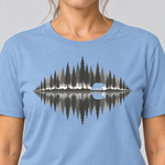 Nahaufnahme des Drucks: Bär am Waldsee – T-Shirt Unisex in Himmelblau, von einer Frau getragen