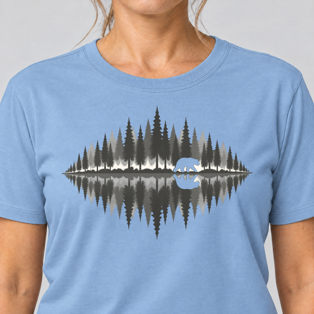 Nahaufnahme des Drucks: Bär am Waldsee – T-Shirt Unisex in Himmelblau, von einer Frau getragen
