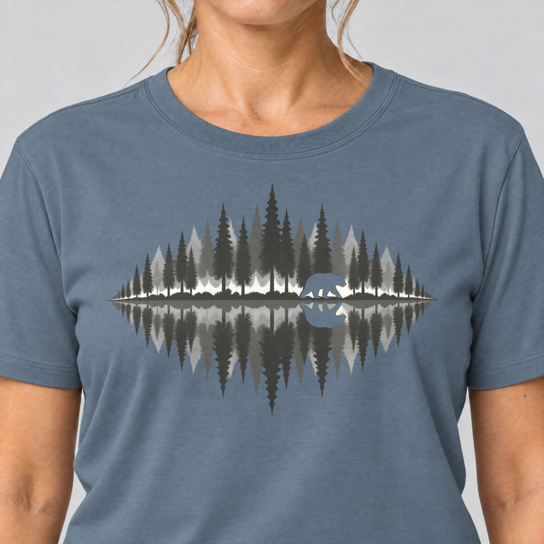 Nahaufnahme des Drucks: Bär am Waldsee – T-Shirt Unisex in Steinblau, von einer Frau getragen