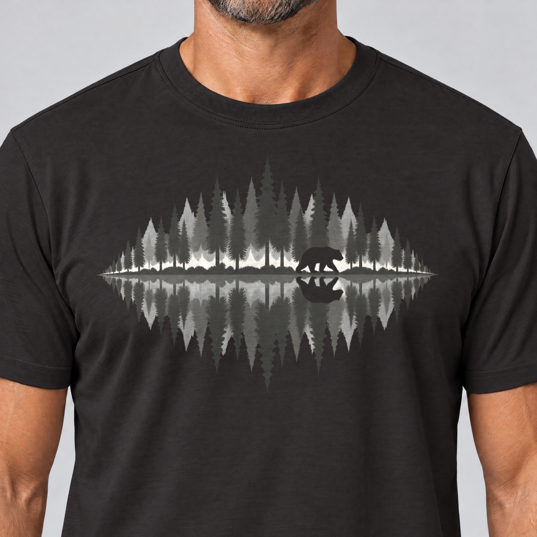 Nahaufnahme des Drucks: Bär am Waldsee – T-Shirt Unisex in Schwarz, von einem Mann getragen