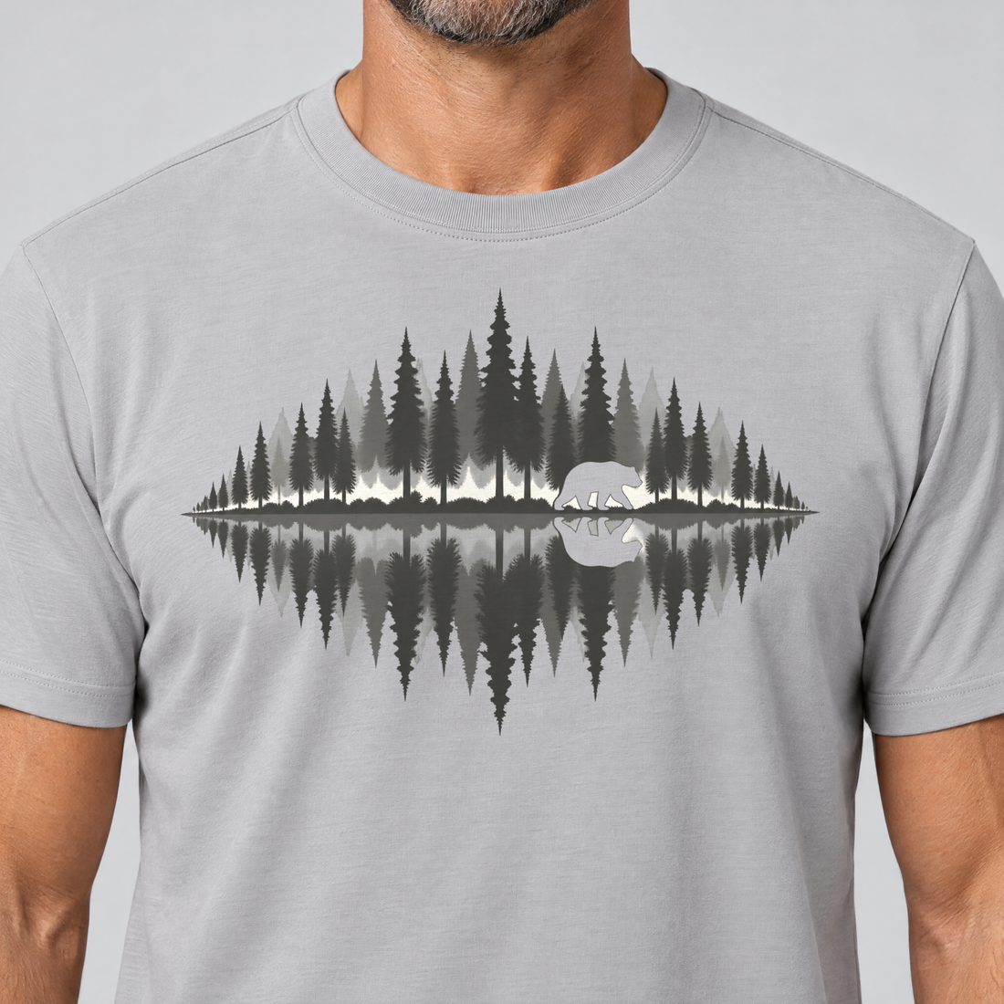 Nahaufnahme des Drucks: Bär am Waldsee – T-Shirt Unisex in Hellgrau, von einem Mann getragen