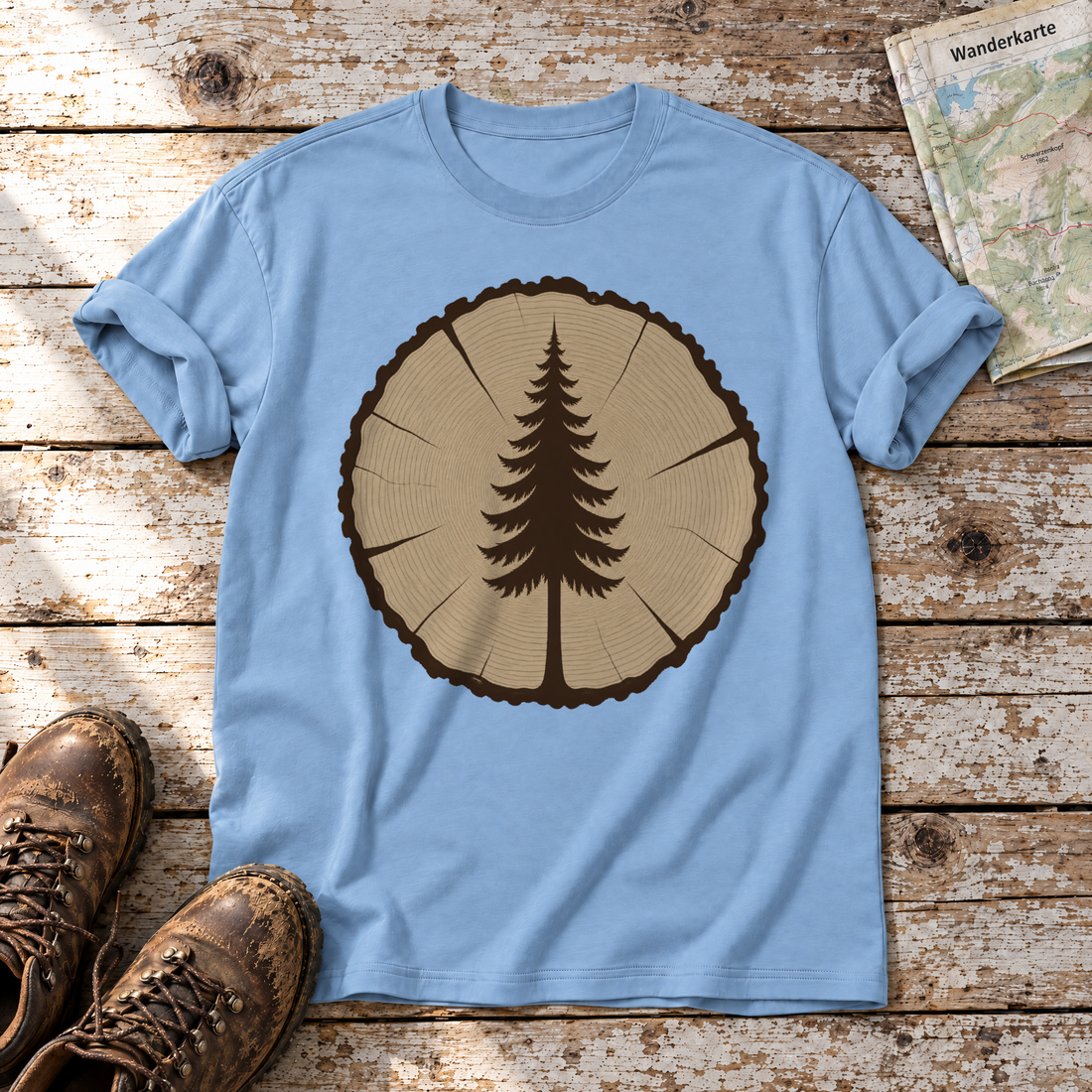 Fichte in der Baumscheibe – T-Shirt Unisex in Himmelblau, flach liegend auf alten Holzbrettern mit Wanderschuhen und Wanderkarte.